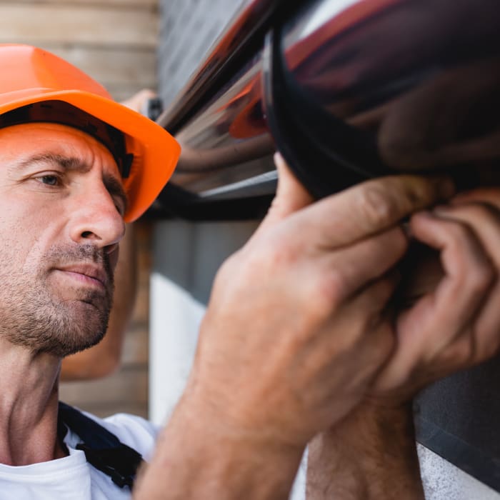 Close up of an employee working on a gutter wearing a hard hat